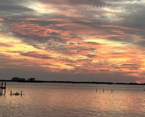 Sunset over a body of water with bright red, orange, and golden-yellow hues in the sky.