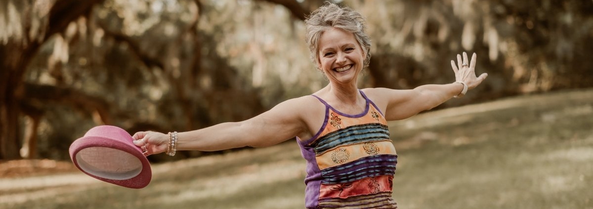 Smiling woman with arms open in a sunny park, representing Tracy Sisk, LMHC, a Clearwater therapist offering compassionate counseling at Honor Your Way Therapy.