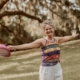 Smiling woman with arms open in a sunny park, representing Tracy Sisk, LMHC, a Clearwater therapist offering compassionate counseling at Honor Your Way Therapy.