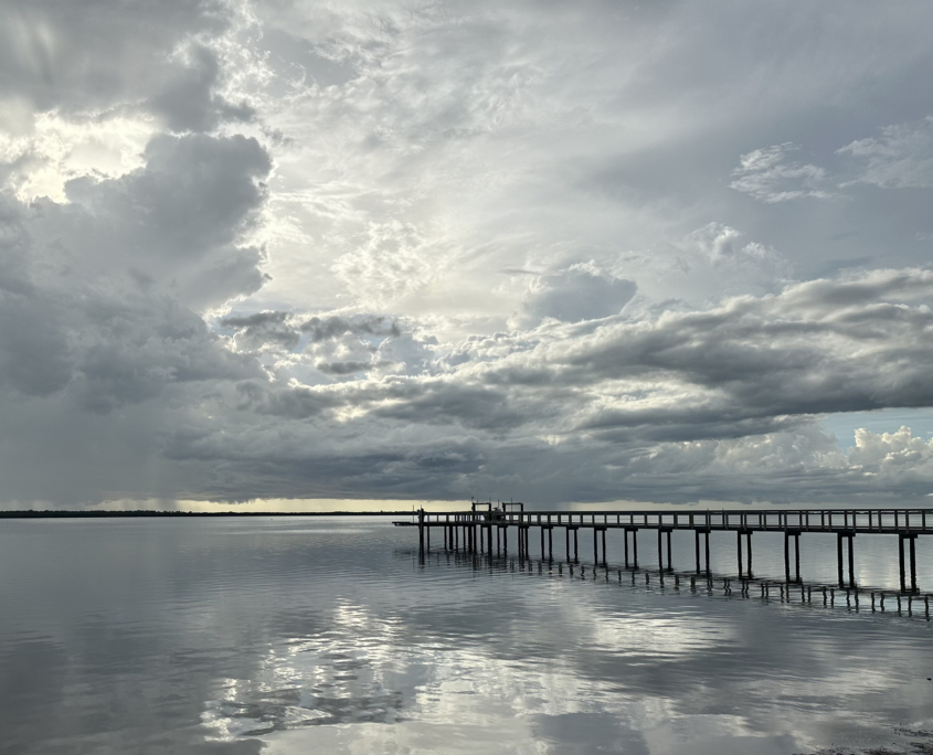 Storm clouds over the water with sunlight breaking through and reflecting on the surface.