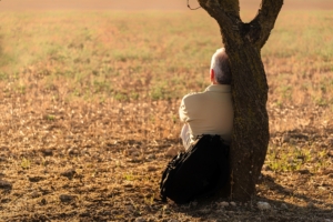 Person resting against a tree representing support through online therapy in Florida